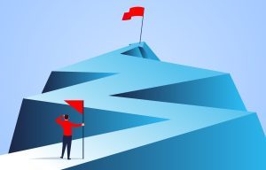 A man standing on a zigzag arrow path, looking in the distance at a goal marked by a flag