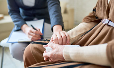 Close up of female psychologist holding hand of senior woman during therapy session, copy space.